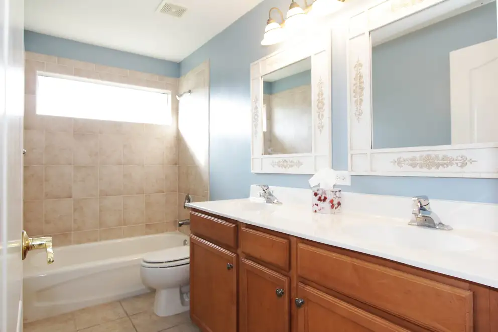A bathroom with a double vanity, two mirrors and a bathtub