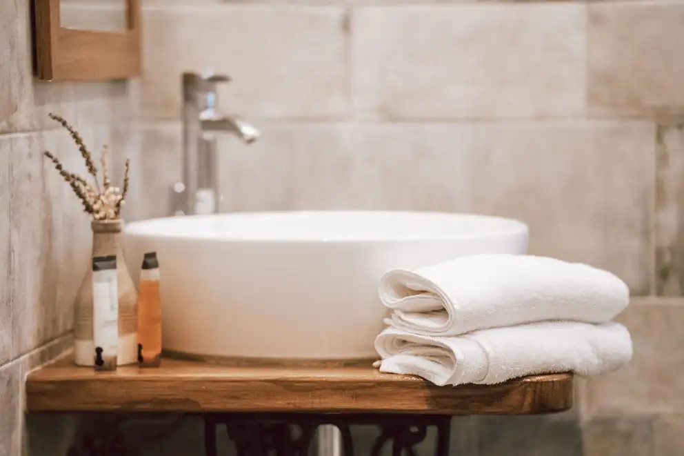 A round basin on a wooden shelf with folded towels