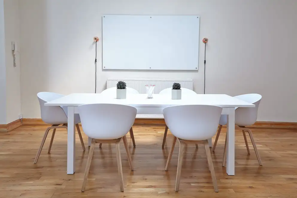 A white meeting room with a whiteboard and six chairs
