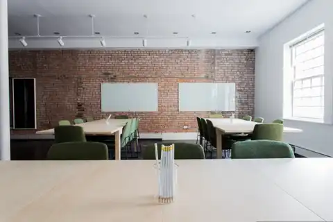 A meeting room with an exposed brick wall and a long clear table