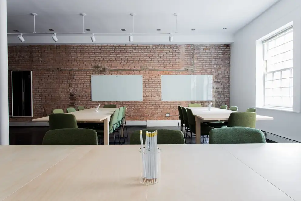 A meeting room with an exposed brick wall and a long clear table