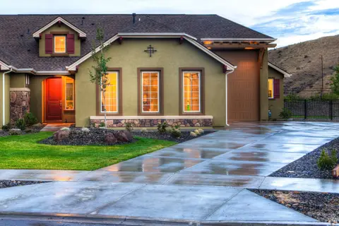 A single-storey stucco house with a red front door and a gravel garden