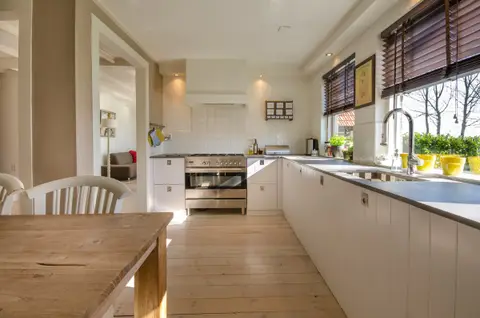 A kitchen with a long worktop and a dining table in the foreground