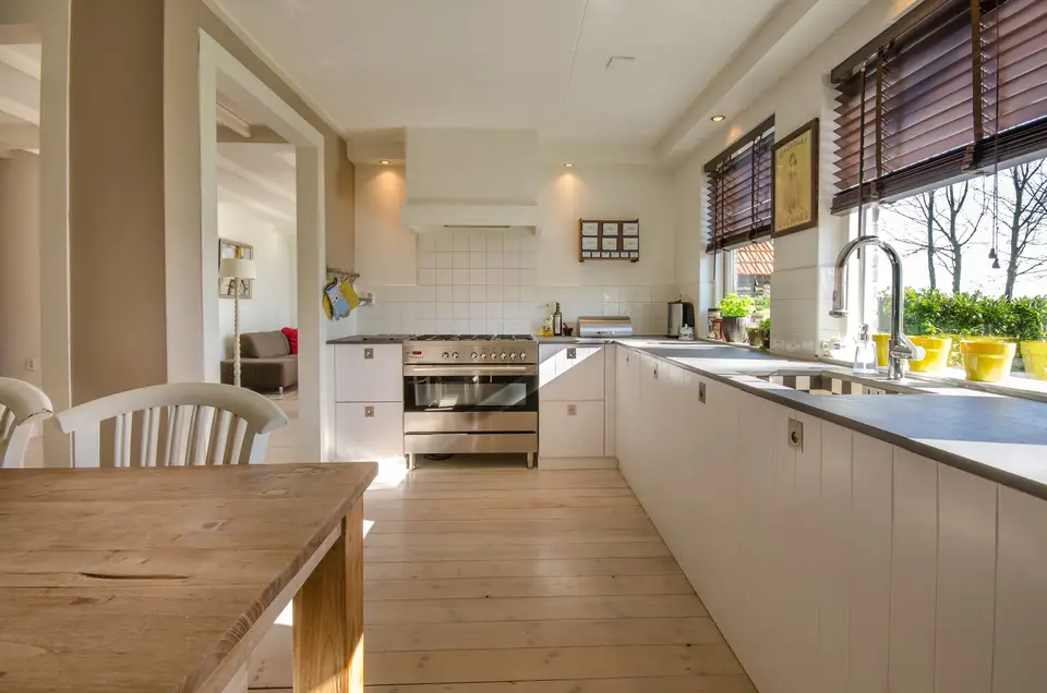A kitchen with a long worktop and a dining table in the foreground