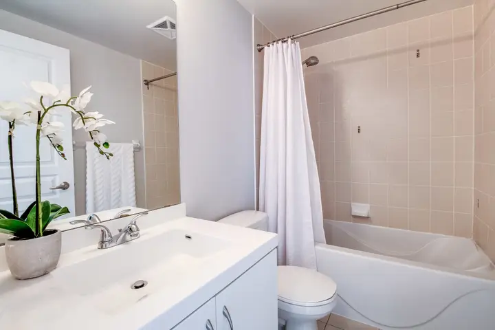 A bathroom with a white vanity, a mirror and a bathtub