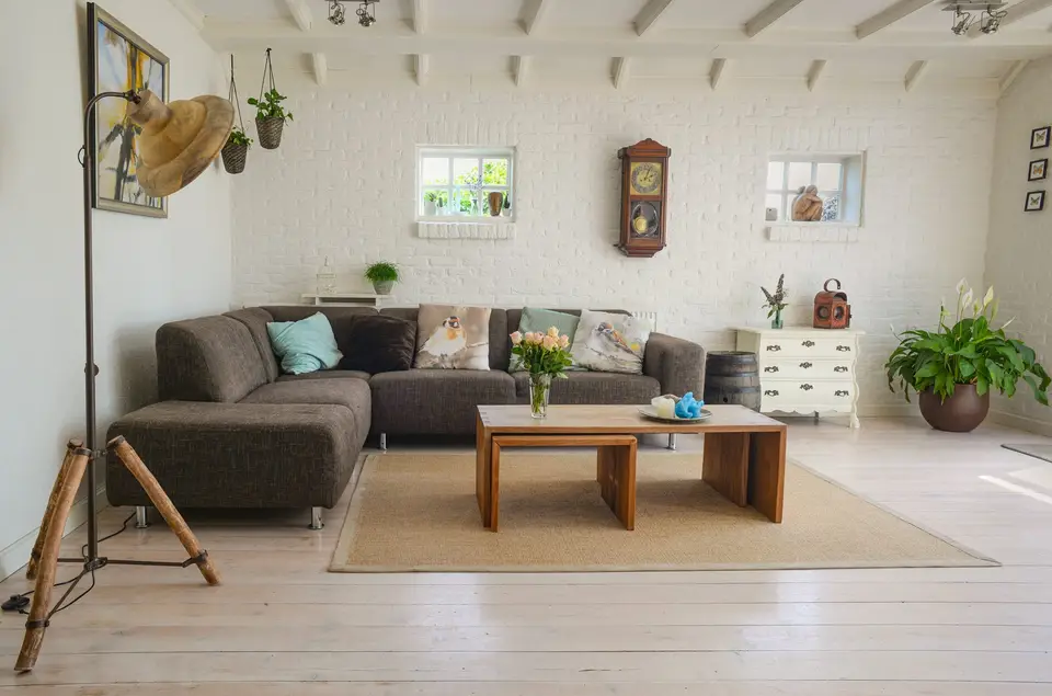 A living room with a sectional sofa, a low wooden table and plants by the window