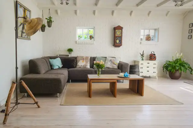 A living room with a sectional sofa, a low wooden table and plants by the window