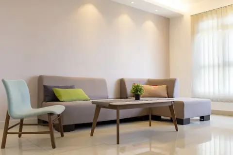 A bright living room with a grey sofa, a wooden coffee table and a pale blue chair
