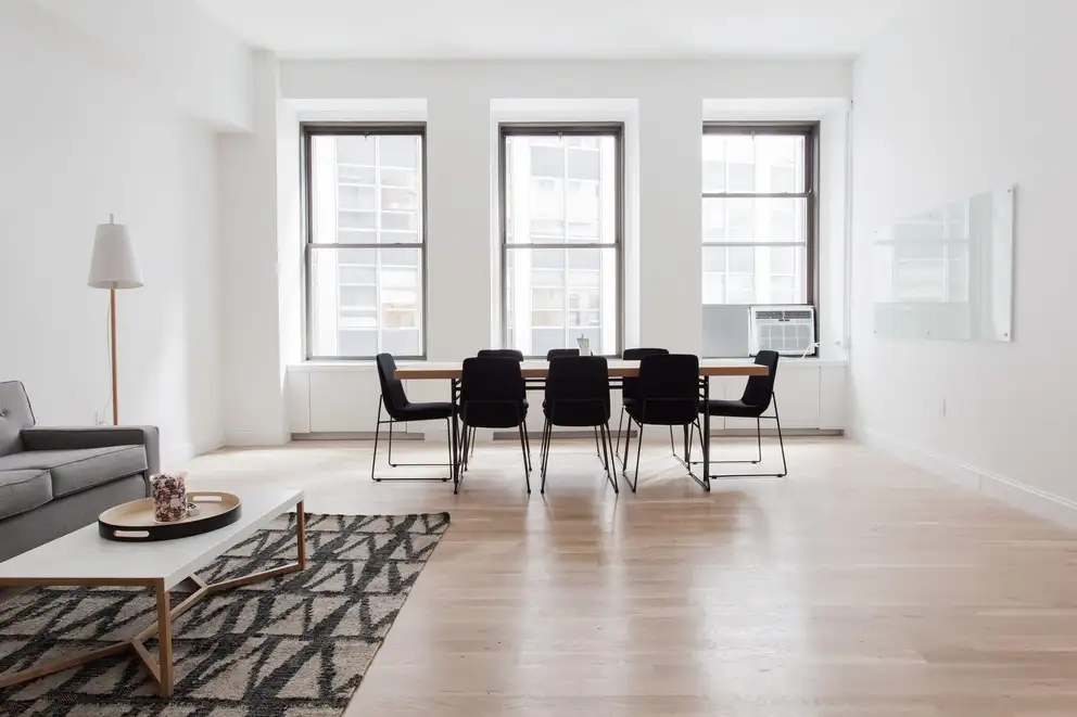 An open living and dining room with a wood floor and three tall windows