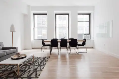 An open living and dining room with a wood floor and three tall windows