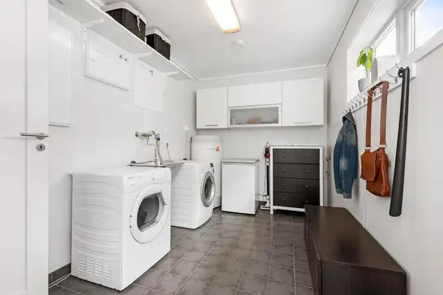 A laundry room with a washer and a dryer under white cabinets