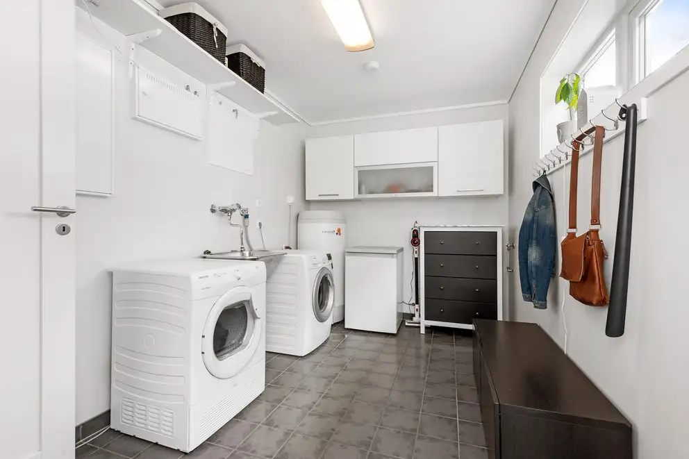 A laundry room with a washer and a dryer under white cabinets