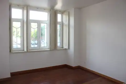 An empty room with a bare wood floor and an open window