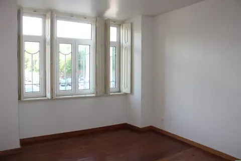 An empty room with a bare wood floor and an open window